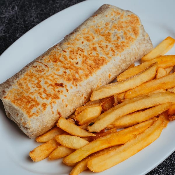 A golden-brown burrito and a pile of crispy french fries are served on a white plate.